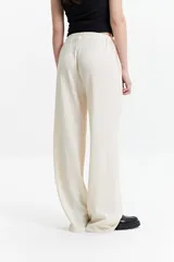 Pantalón de vestir de tiro alto, color crema, con textura crepe arrugada y pierna ancha y fluida. Presenta cintura elástica.