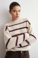 Sweater de tejido de punto grueso con diseño de rayas horizontales en tonos azul y rojo sobre base color natural, cuello redondo y mangas largas.
