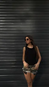 Short de jean con estampado de camuflaje en tonos verde, marrón y beige, con terminaciones desflecadas.