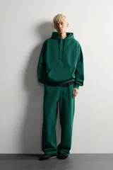 Pantalón jogger de corte relajado y pernera ancha, confeccionado en tejido de algodón con interior perchado. Cuenta con cintura elástica ajustable mediante cordón interior, bolsillos laterales y un bolsillo trasero de plastrón.