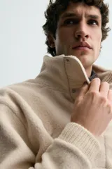 Sudadera de corte relajado confeccionada en tejido con textura de borreguillo, con cuello subido y cierre frontal de botones a presión. Presenta puños y ruedo con acabado en rib.