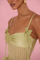 Vestido largo Patbo de color verde, confeccionado con un cuerpo de tejido tipo red transparente y detalles de tela lisa en el busto y cadera. Cuenta con breteles finos ajustables con detalles florales colgantes.