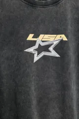 Remera oversize de efecto lavado en color gris oscuro, con cuello redondo, manga corta y estampa frontal de una estrella y el texto 'LISA'.
