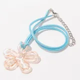 Collar con dije de flor transparente con reflejos iridiscentes y cordón fino celeste.