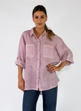 Camisa de lino color rosa, de corte holgado, con cuello camisero, bolsillos frontales con solapa y mangas largas con presilla para arremangar.