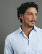 Camisa de vestir de manga larga en color celeste, con cuello clásico, cierre frontal de botones y bolsillo en el pecho.