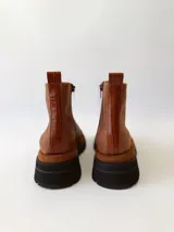 Botas cortas de cuero color marrón con elástico en los laterales y detalle de cuero texturizado en la parte delantera.