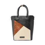 Matera de diseño vertical con paneles combinados en texturas de cuero sintético con efecto croco en colores negro, marrón y beige. Cuenta con doble asa superior y placa metálica con el logo de la marca en la parte frontal.