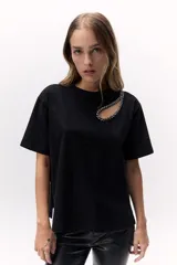 Remera negra de algodón con cuello redondo y manga corta. Presenta un calado en el hombro con detalle de pedrería.