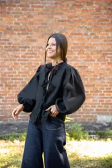 Blusa de lino color negro con mangas abullonadas y cierre frontal mediante lazos ajustables. Presenta un diseño de silueta relajada y escote con abertura.
