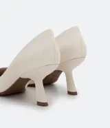 Zapato scarpin color blanco hueso, con puntera fina y taco fino diferenciado de 8 cm de altura. Fabricado en poliuretano.
