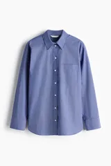 Camisa de corte oversized confeccionada en popelina de algodón con diseño de microcuadros. Presenta cuello clásico, bolsillo de parche en el pecho, cierre frontal con botones, hombros caídos y mangas largas con puños abotonados. Incluye canesú con pliegue en la espalda y bajo recto con aberturas laterales redondeadas.