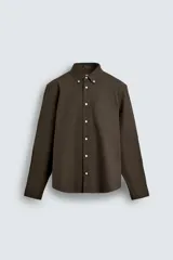 Camisa de corte regular confeccionada en tejido de algodón, con cuello abotonado, manga larga con puños abotonados, bolsillo plastrón en el pecho y cierre frontal de botones.