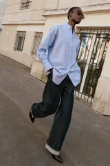 Camisa de corte oversize con cuello solapa, manga larga con puños y bajo asimétrico. Cierre frontal con botones.