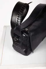 Cartera tipo baguette confeccionada en cuero de color marrón oscuro, con diseño alargado, cierre diagonal y correa de hombro.