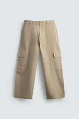 Pantalón cargo de corte relajado confeccionado en tejido de algodón con elasticidad. Presenta bolsillos laterales tipo plastrón con solapa en las perneras, bolsillos frontales y bolsillos traseros de doble vivo. Cierre frontal con cremallera y botón.