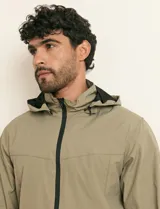 Campera impermeable gris con capucha, cierre frontal y bolsillos laterales con cremallera.