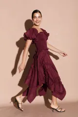 Falda midi asimétrica color bordó, con volados decorativos en espiral y cierre lateral.