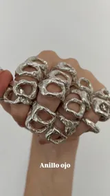 Anillo de diseño orgánico con textura irregular y acabado plateado, con una forma central abierta que evoca un ojo.