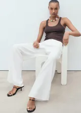 Pantalón blanco de tiro medio, corte recto y largo, con cierre de cremallera y botón, cinco bolsillos y tejido 100% algodón.