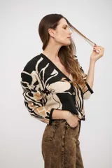 Saco tejido de punto con diseño animal print abstracto en tonos negro, beige y tostado. Presenta escote en V, cierre frontal con botones y mangas largas con puños ajustados.