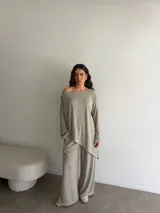 Conjunto gris melange compuesto por un buzo de cuello bote amplio y corte asimétrico con bolsillos, y un pantalón largo de corte recto y holgado.