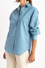 Camisa celeste con rayas verticales blancas, de corte oversize y manga larga.