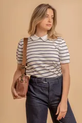 Bandolera de diseño moderno y funcional, confeccionada en nylon color marrón claro. Cuenta con múltiples compartimentos con cierre metálico, herrajes plateados y una correa ancha ajustable con detalle de marca.