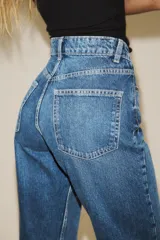 Jeans de tiro alto color negro con efecto lavado, corte mom fit, cinco bolsillos y cierre frontal con cremallera y botón metálico.