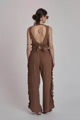 Conjunto de dos piezas color rojo, compuesto por un top sin mangas con detalle de volado fruncido en el bajo y un pantalón ancho de tiro alto con volados largos a lo largo de las costuras laterales exteriores.