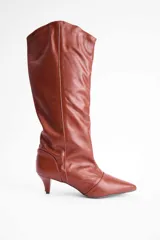 Bota de caña alta confeccionada en cuero vacuno color suela, con diseño de punta fina y taco kitten heel.