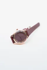 Reloj analógico con caja redonda color oro rosado, esfera blanca con números arábigos en color oro rosado y correa de cuero blanco texturizado.