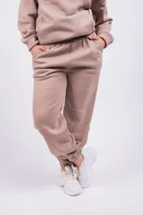 Pantalón de jogging color beige con cintura elástica y logo estampado en blanco en el muslo.