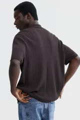 Camisa de punto acanalado color marrón, de corte regular, con cuello tipo polo y cierre frontal con botones.