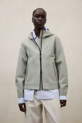 Campera impermeable Ecoalf modelo Venis, color verde militar, con capucha, cierre frontal de cremallera y bolsillos laterales. Confeccionada en tejido técnico de poliéster reciclado.