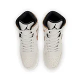 Championes de media caña Air Jordan 1 Mid color beige con detalles en marrón y negro. Presentan el logo de Jordan en el lateral y suela blanca con base negra.