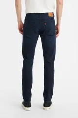 Jean de corte skinny y tiro medio, en color azul oscuro con acabado uniforme. Presenta costuras reforzadas y cierre frontal con botón y cremallera.