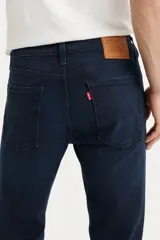 Jean de corte skinny y tiro medio, en color azul oscuro con acabado uniforme. Presenta costuras reforzadas y cierre frontal con botón y cremallera.