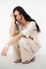 Pantalón de lino color beige con brillo, de corte palazzo y tiro alto.