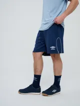 Bermuda deportiva Umbro modelo Veliz para hombre, color negro con detalles en blanco, cordón ajustable en la cintura y logo bordado en la pierna izquierda.
