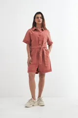 Mono corto color ladrillo, con cuello camisero, mangas cortas con dobladillo, cierre frontal con botones y cinturón de lazo.