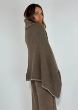 Ruana de lambswool color gris oscuro, con cuello alto y detalles bordados a mano en relieve en el cuello y a lo largo de la abertura frontal.