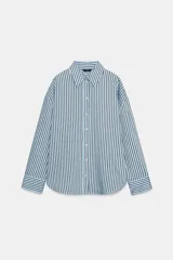Camisa de corte oversize con estampado de rayas verticales en tonos celeste y negro. Presenta cuello solapa, cierre frontal con botones y mangas largas con puños rectos.