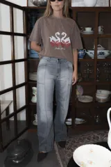 Jean de corte recto y tiro medio, con costuras verticales decorativas en el frente que estilizan la silueta. Presenta un diseño de cinco bolsillos y bordado de brújula en los bolsillos traseros.