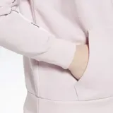 Campera con capucha Reebok de mujer, color lila, con cierre frontal completo, bolsillos tipo canguro y ribetes con el logo de la marca en las mangas. Corte oversize.
