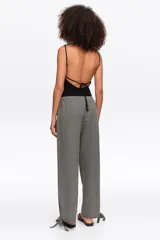 Pantalón de corte recto y tiro medio, con estampa de cuadros en blanco y negro. Posee cintura elástica y detalles de lazos ajustables en los tobillos.