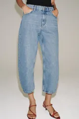 Jeans capri balloon leg de tiro medio en color celeste, con trabillas para cinto, bolsillos delanteros y traseros, y cierre frontal con botón y cremallera.