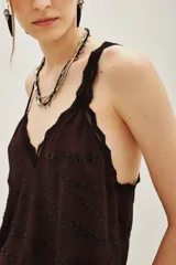 Top negro con escote en V y tirantes finos, ambos con detalles de encaje. Presenta un diseño de cadenas bordadas con cuentas en la parte frontal.