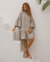 Vestido corto de lino color beige, con cuello mao, cierre frontal abotonado con botones de nácar, mangas acampanadas con volados, bolsillos laterales y falda con volado en el ruedo.