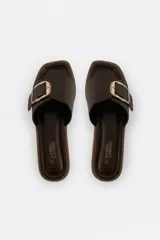 Sandalias Daniel Cassin de símil cuero color marrón oscuro, con una tira ancha cruzada en el empeine y una hebilla metálica rectangular dorada. Presentan puntera cuadrada y suela plana.